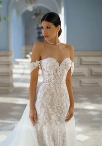 Detailed embroidery of plant patterns on a white lace mermaid wedding dress with trailing veil