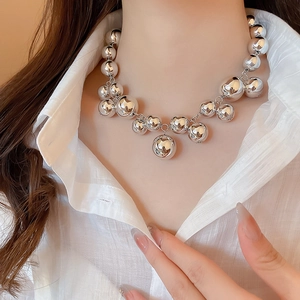 Detailed view of silver metallic spheres in varying sizes on a stylish fringe necklace