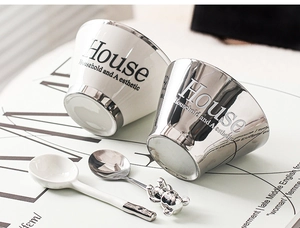Detail of Nordic ceramic mugs and bear-shaped silver spoons set for home use