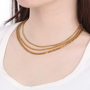 Close-up of triple layered 18K gold plated Cuban chain necklaces worn by a model