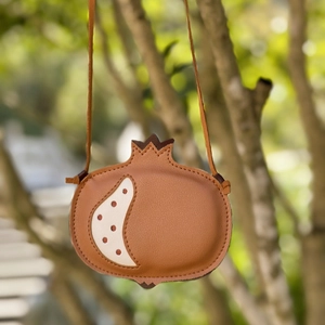 Unique pomegranate-shaped crossbody bag for kids with brown lychee texture hanging on branch