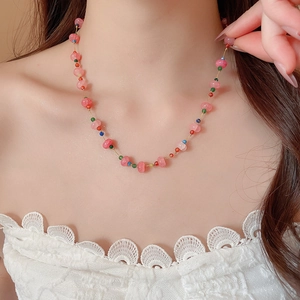 Macro detail of pink crystal beaded necklace with colorful accents on a gold-plated chain