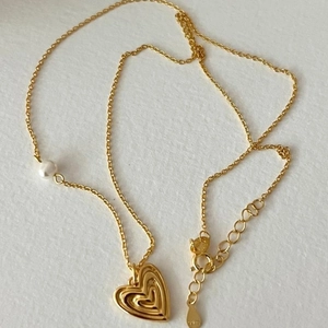 925 silver heart necklace with white pearl pendant on textured background