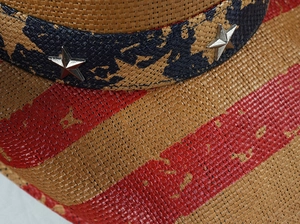 Detailed macro of woven straw cowboy hat featuring silver stars and American flag stripes