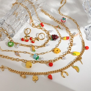 Close-up of golden stainless steel fruit necklaces and bracelets with colorful charms