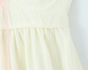 Dettaglio dell'abito beige in stile francese con nastro rosa e trama del tessuto