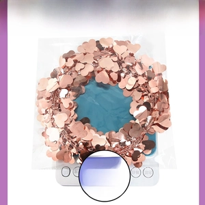 Macro shot of 30g rose gold heart sequin garland in a transparent bag on weighing scale