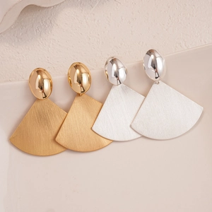 Elegant gold and silver fan-shaped geometric earrings with brushed metal finish on a tray