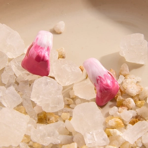 Detailed close-up of pink and white marble textured resin earrings on natural salt crystals