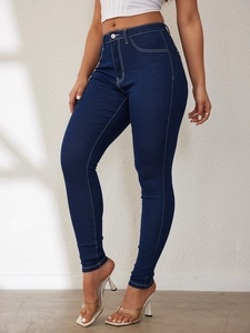 Detail of high-waist dark blue jeans with white contrast stitching and slim fit design