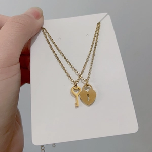 Gold-plated titanium steel necklace with heart-shaped lock and key pendant on display
