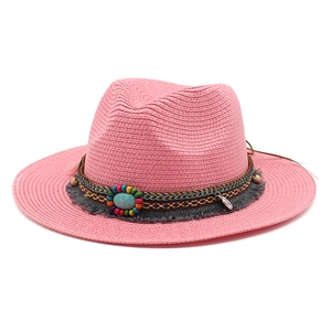 Detailopname van roze strohoed met boho kralenband en blauwe siersteen