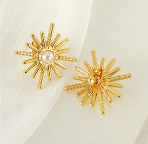 Détail de boucles d'oreilles étoiles dorées avec perle blanche sur fond en soie