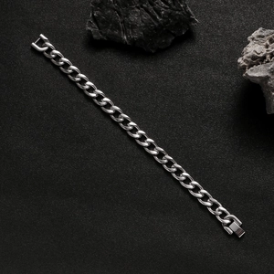 Silver stainless steel Cuban link chain bracelet shown on a dark grey rock texture