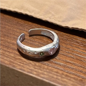 Macro detail of S925 sterling silver matte ring with pink heart and green gemstone