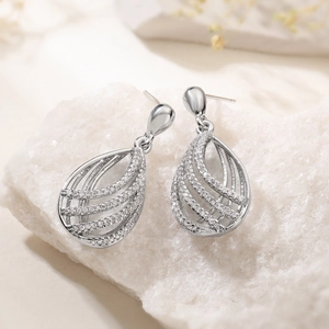 Elegant silver hollow teardrop earrings with crystals on a white crystal stone base