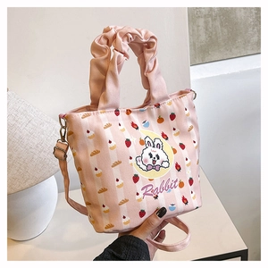 Detail view of pink strawberry canvas bucket bag with cute rabbit print and ruffled handle