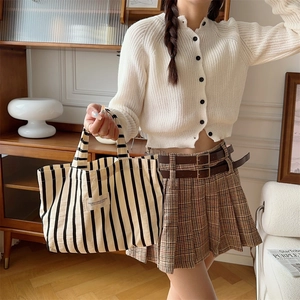 Detail of black and white striped canvas tote bag with woven label shown on model