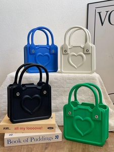 Detailed close-up of colorful EVA beach bags with 3D heart motifs on a minimalist setup