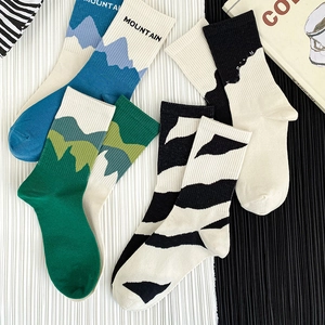 Asymmetric mountain and zebra pattern cotton crew socks shown in a flat lay arrangement