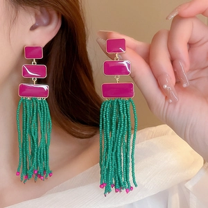 Bohemian drop earrings featuring magenta rectangles and vibrant green beaded tassels