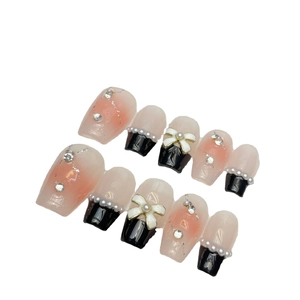 Pink blush gradient press-on nails with black French tips, 3D bows, and pearls