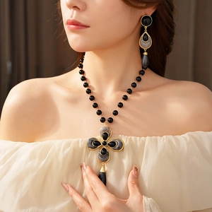 Detail of vintage floral cross necklace and teardrop earrings on a female model