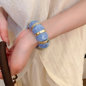Close-up of light blue marble resin bracelet with gold metal rings on a female wrist