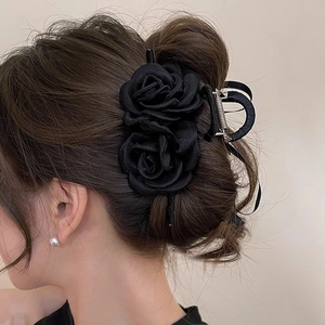 Elegant black rose hair claw clip in silk texture worn on a bun for a chic French style
