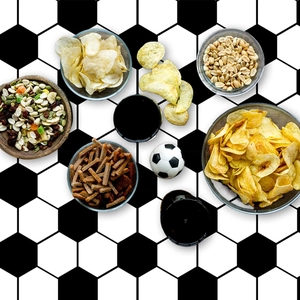 Flat lay of disposable football tablecloth with snacks and party drinks for match day