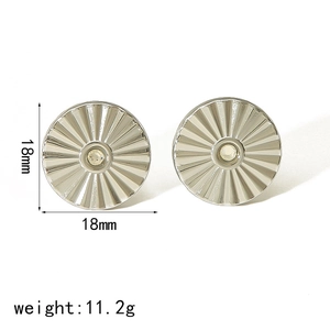 Detailed macro view of silver 18mm round steel earrings with radial texture and center dot