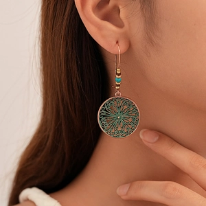 Close-up of model wearing vintage boho round drop earrings with turquoise beads