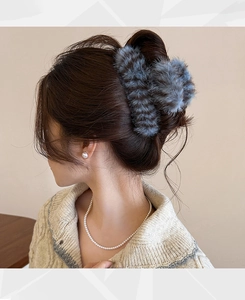Detail of grey striped faux fur hair claw clip worn on model's dark brown hair