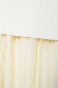 Detailed view of white knit fabric stitched with pleated pale yellow tulle skirt material