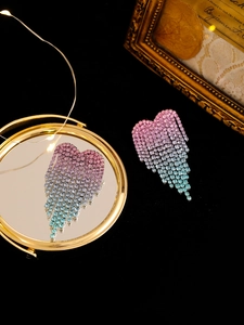 Macro detail of rhinestone heart tassel earrings with pink and blue gradient crystal finish
