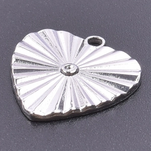 Macro shot of silver heart pendant with radiant sunburst texture and 18k plating