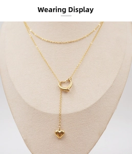 Detailed view of gold hollow heart Y-shaped lariat necklace on a beige jewelry display