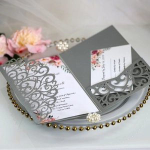 Elegant laser cut grey pearl paper wedding invitation set with RSVP card on a gold plate