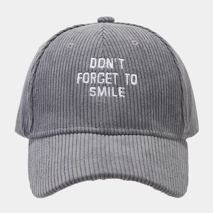 Detail of grey corduroy baseball cap with white embroidered Don't Forget To Smile slogan