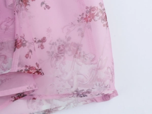 Detail of pink floral organza fabric with vintage angel and rose prints and stitched hem