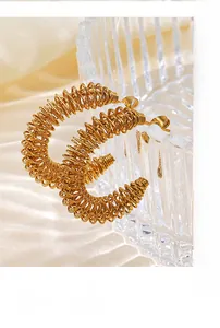 Détail macro de boucles d'oreilles spirales dorées sur un fond de soie douce