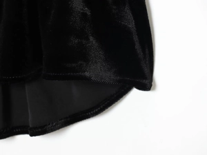 Dettaglio del tessuto in velluto nero drappeggiato e delle finiture delle cuciture