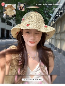 Detail of straw sun hat with red strawberry embroidery and natural woven texture