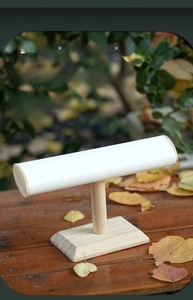 Macro shot of single-tier wooden jewelry stand with premium white leather cylinder bar