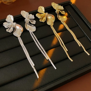 Detail von gold- und silberfarbenen Blumen-Ohrringen mit Metallketten auf dem Display