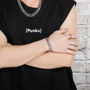 Close-up of men's chunky silver Cuban link necklace and bracelet set with vintage ring