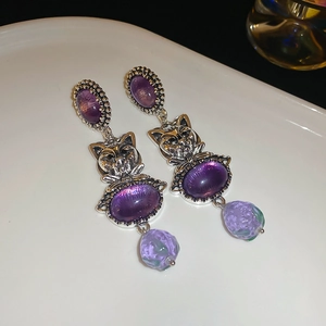 Close-up of vintage cat earrings with purple crystals and silver metal cat head relief