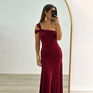 Détail de la fente latérale et du drapé sur une robe bordeaux à une épaule dénudée