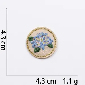 Macro view of blue floral embroidery patch with gold metallic edge 4.3cm diameter