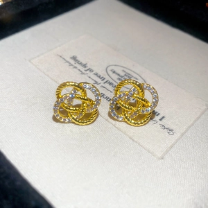 Vue macro de boucles d'oreilles nœud dorées avec zircons étincelants pavés